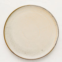 1: A round ceramic plate in matte cream glaze with subtle speckled texture.