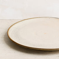 2: A round ceramic plate in matte cream glaze with subtle speckled texture.