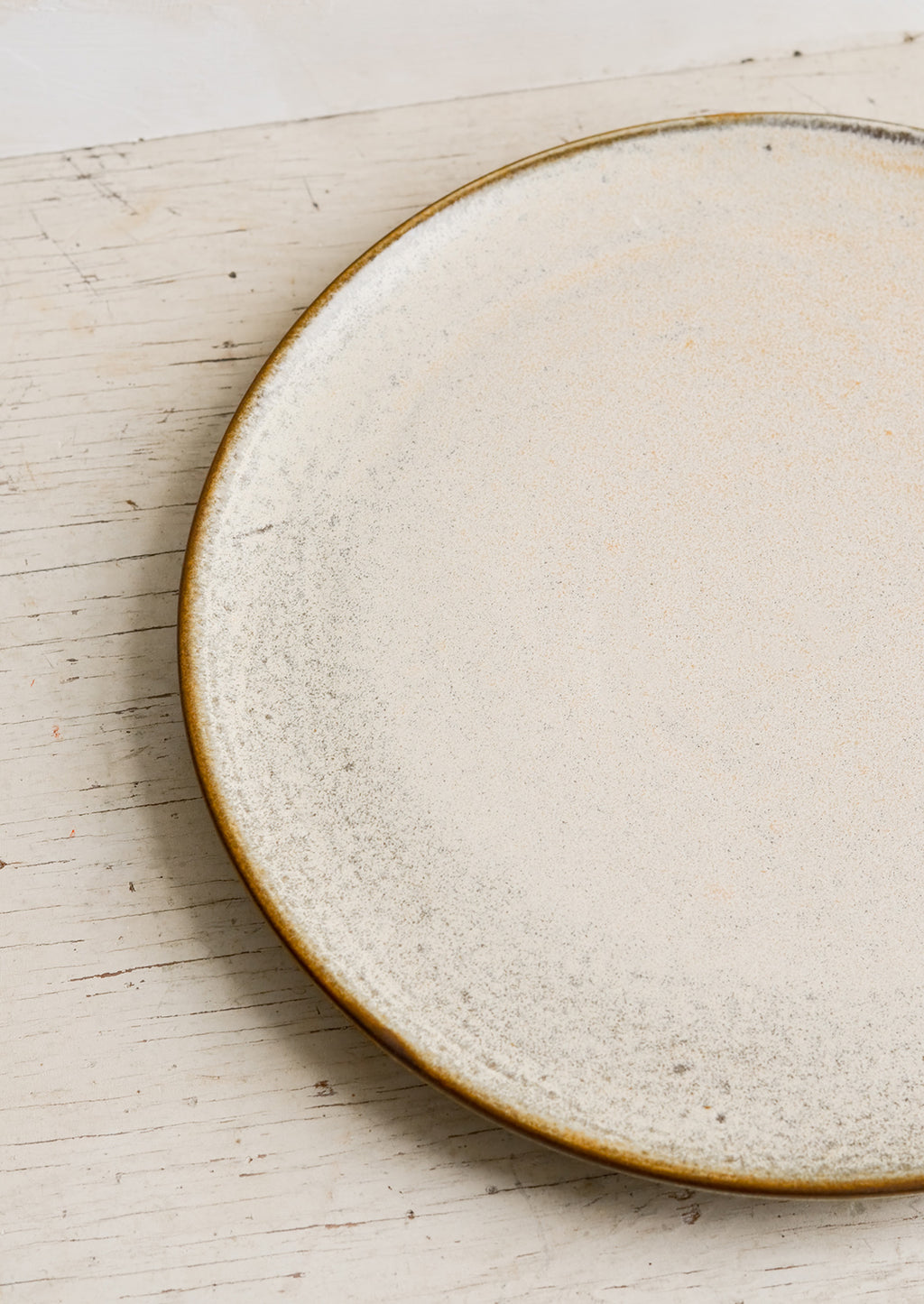 3: A round ceramic plate in matte cream glaze with subtle speckled texture.