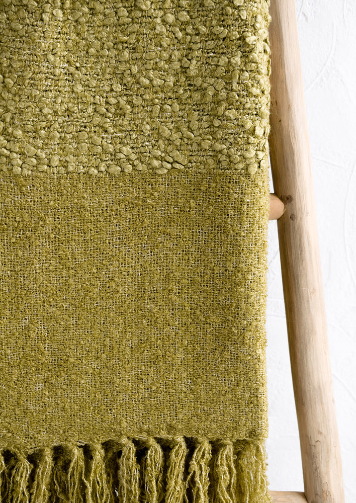 A moss green boucle throw with tassel trim.