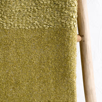 2: A moss green boucle throw with tassel trim.