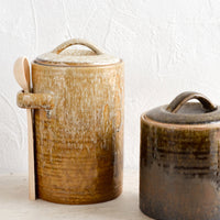 1: Two ceramic storage jars in short and tall sizes, glazed in light and dark brown glazes.