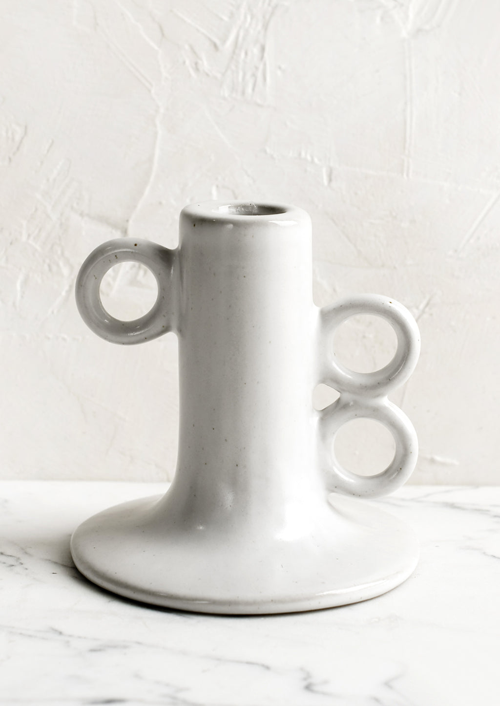 1: A sculptural taper candle holder in white ceramic.