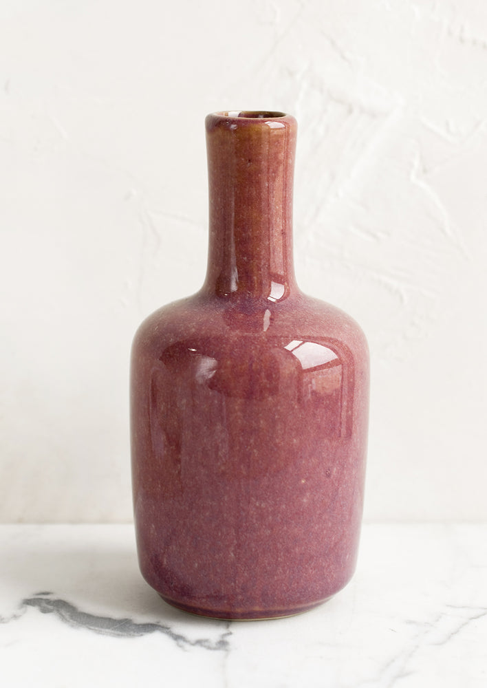 A ceramic bud vase in tall shape, elderberry color.