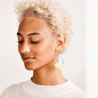 2: Model wearing blue and brass circular earrings