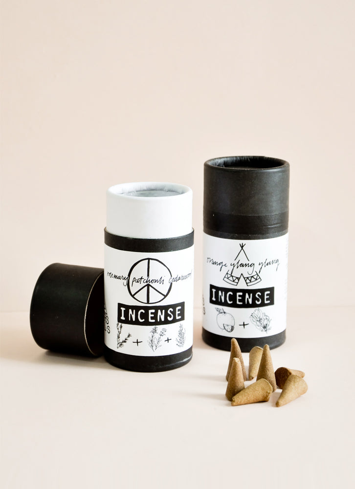 Two black cylinder cartons with white label and black text. Pile of brown cone shaped incense on the right side.