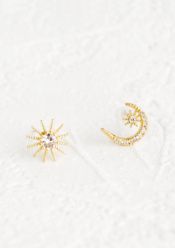 1: A pair of mismatched stud earrings, one piece is a sun and one piece is a moon.