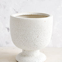 1: A planter in matte light grey textured glaze and footed urn shape.