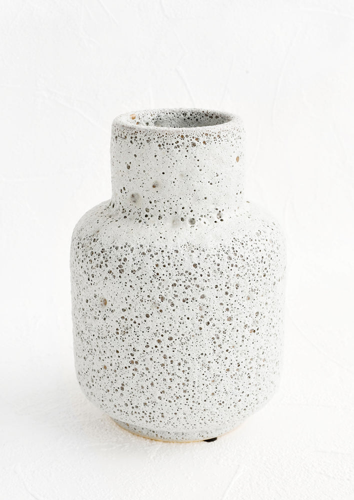 1: A ceramic vase in a heavily textured, crater-like light grey glaze with tapered opening.