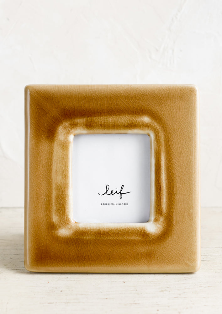 A square ceramic photo frame in crackled brown glaze.
