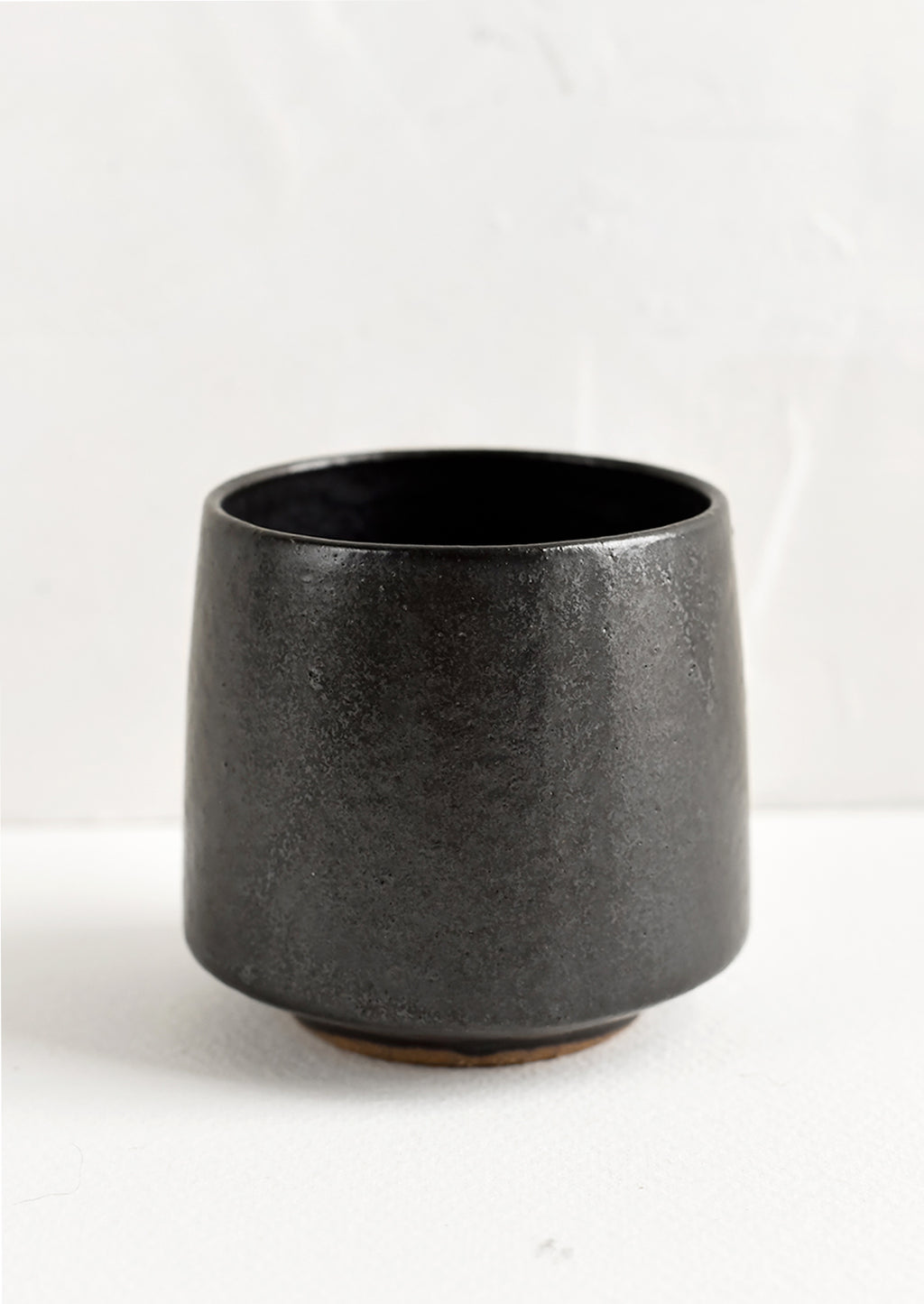 Black: A small footed ceramic cup in satin black glaze.