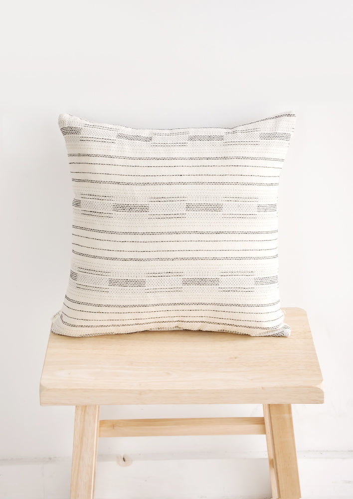 Square pillow in ivory with black variegated stitching in assorted line patterns
