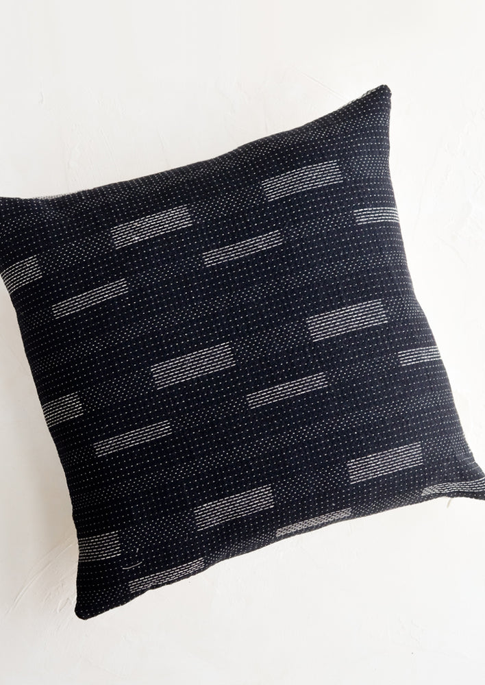 Square pillow in black with white variegated stitching in assorted line patterns