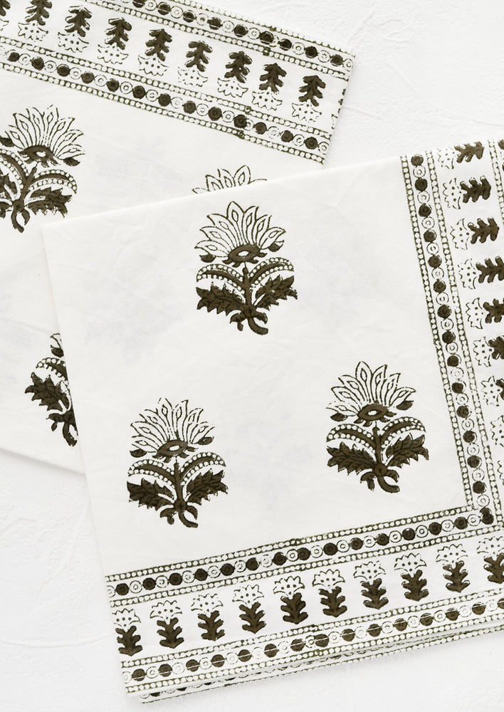 A pair of white napkins with block printed motif in moss green.