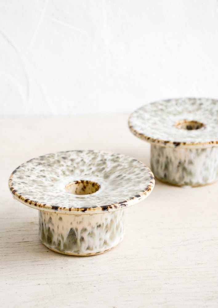 Short ceramic taper candle holders with saucer-like top in speckled reactive glaze