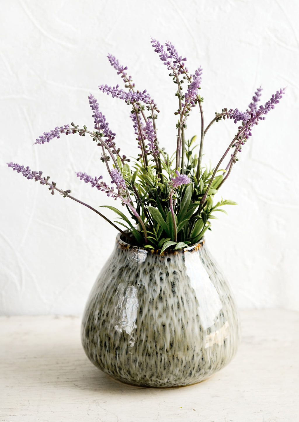 2: A round vase in glossy, speckled green glaze with lavender flowers.