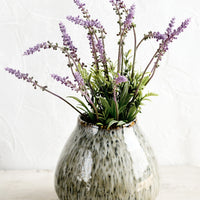 2: A round vase in glossy, speckled green glaze with lavender flowers.
