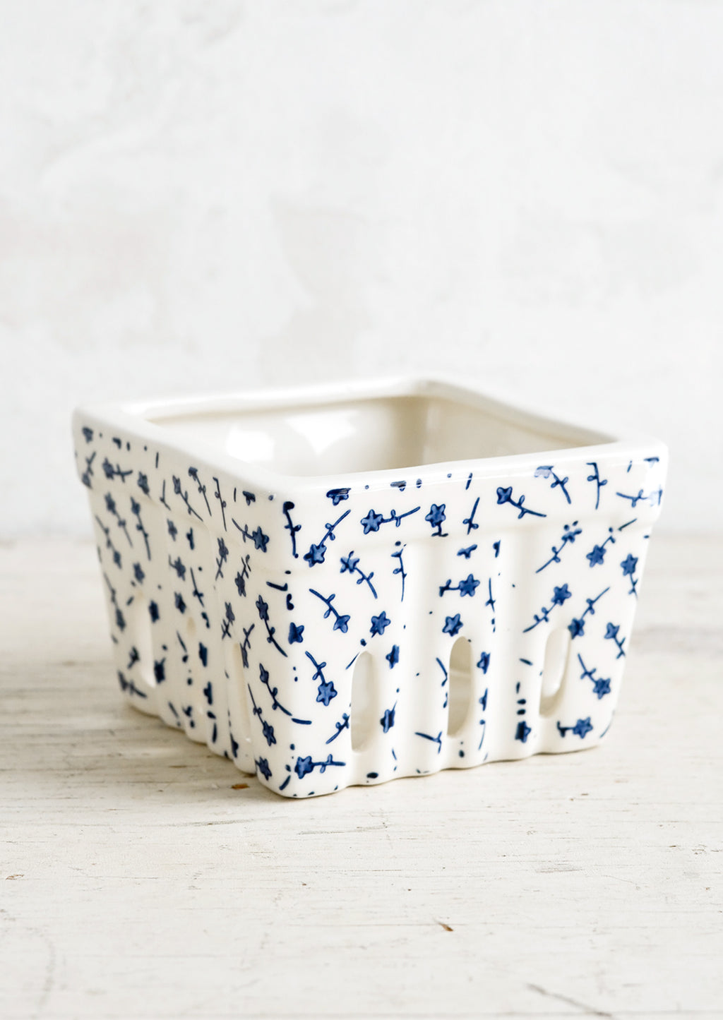 Blue Flowers: A ceramic berry basket  with blue ditsy floral print on white ceramic.