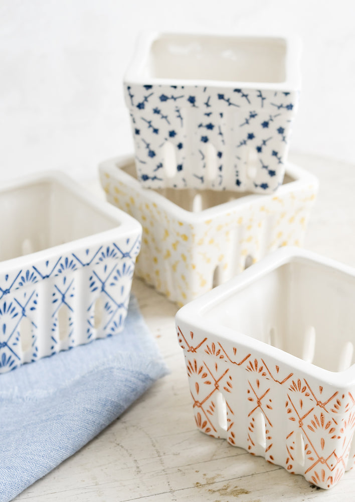 White ceramic berry baskets in primary colors and assorted patterns.