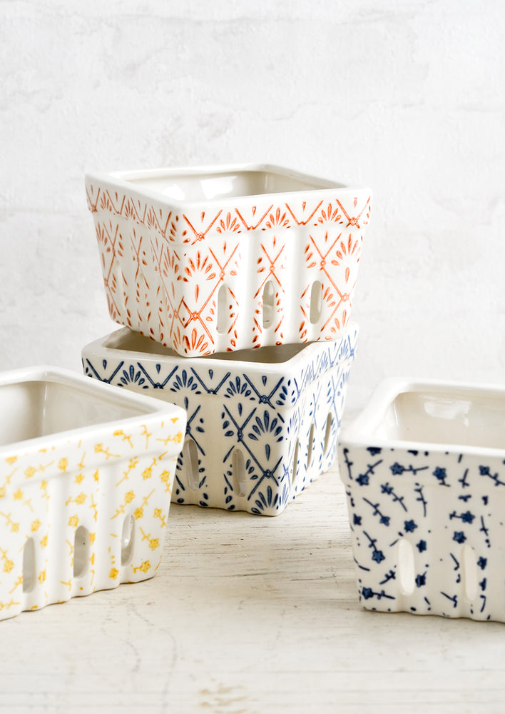 White ceramic berry baskets in primary colors and assorted patterns.