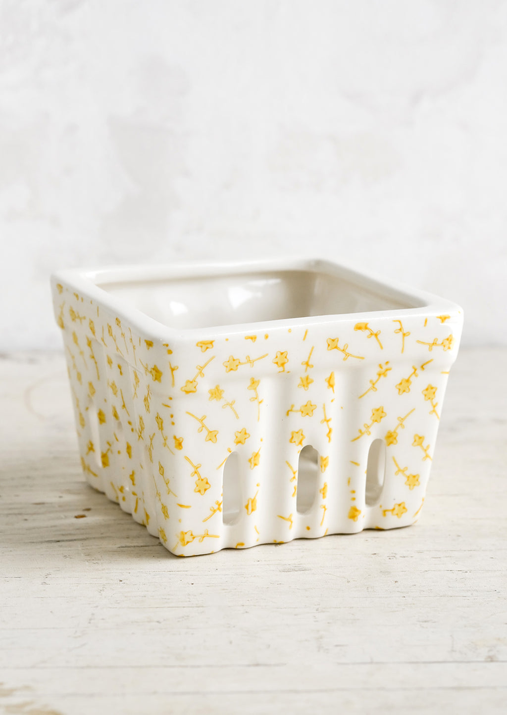 Yellow Florals: A ceramic berry basket  with yellow ditsy floral print on white ceramic.