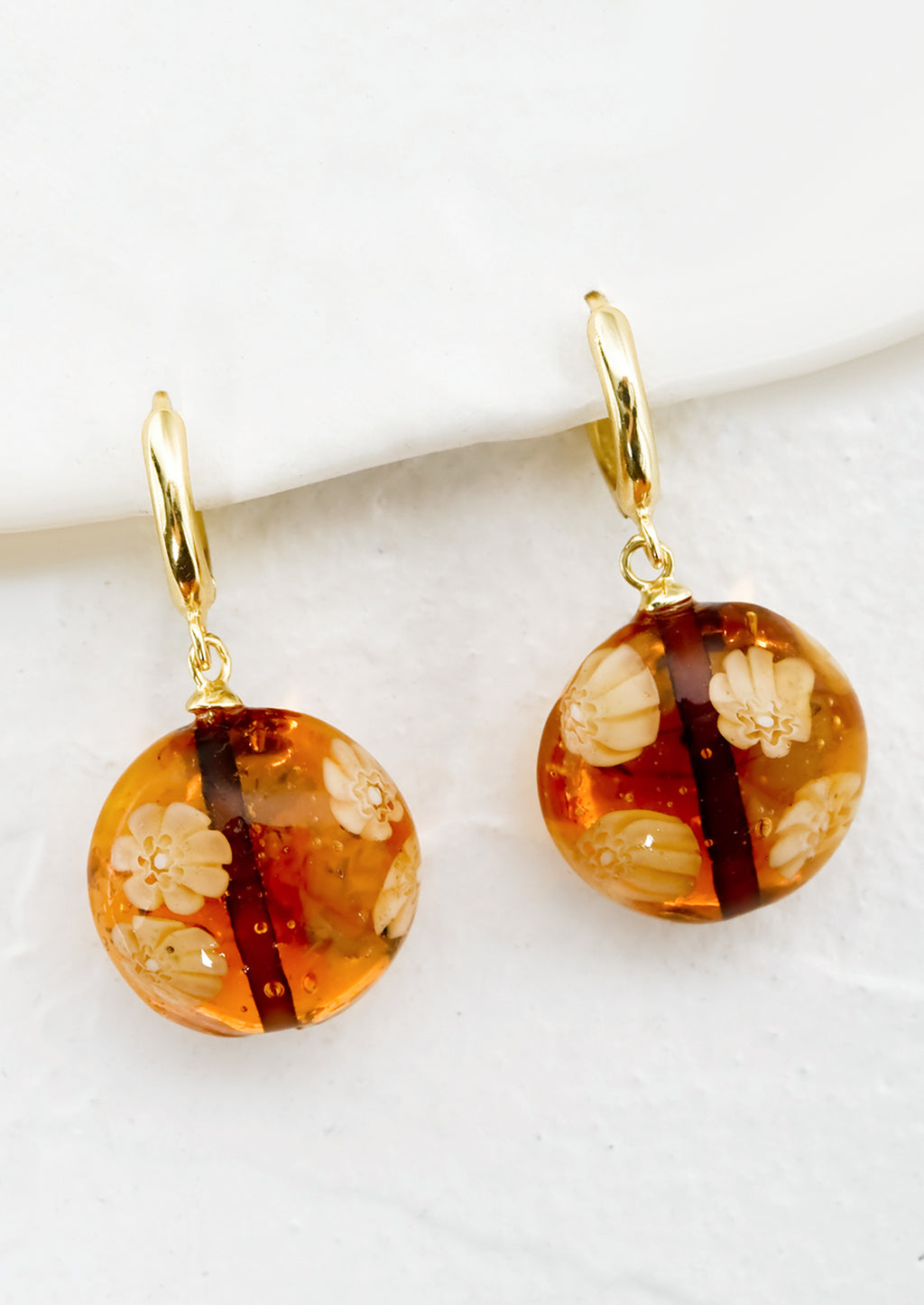 Sepia: A pair of gold huggie hoops with sepia murano glass beads.
