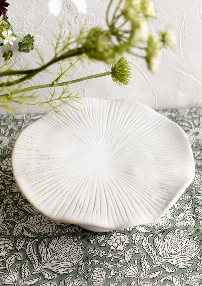 A white ceramic pedestal in the shape of a mushroom with flat top.