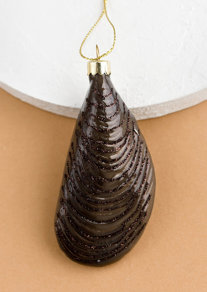 A decorative glass ornament in the shape of a brown mussel shell.