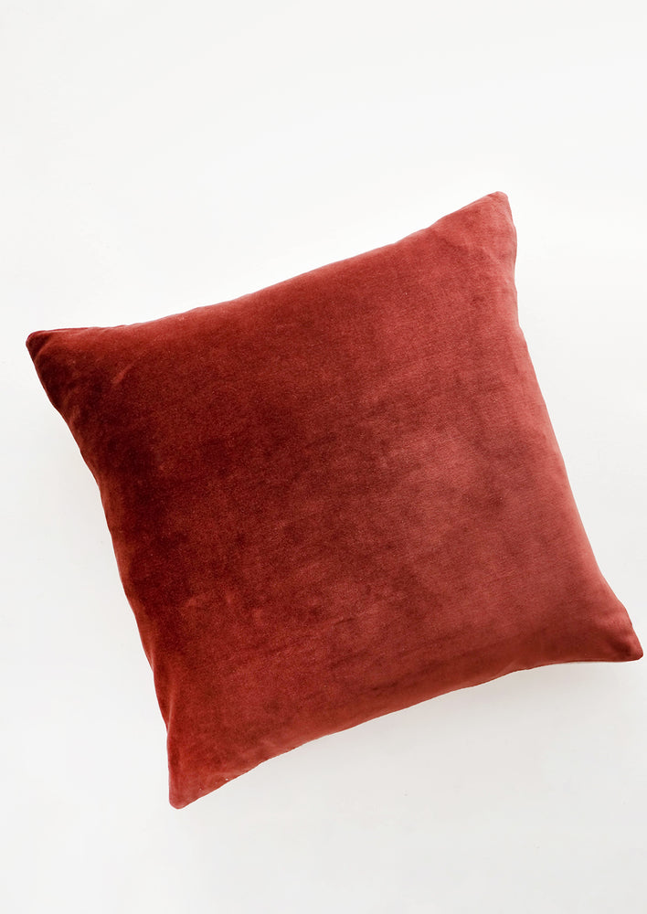A square velvet throw pillow in wine red.