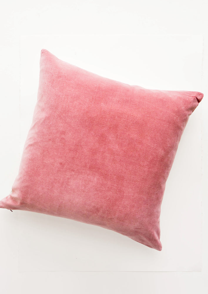 A square velvet throw pillow in dusty pink.