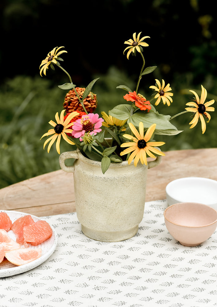A vintage inspired vase with flowers on a table.