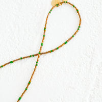 Coffee / Green: A strand of seed beads in coffee and green with brass charm details.