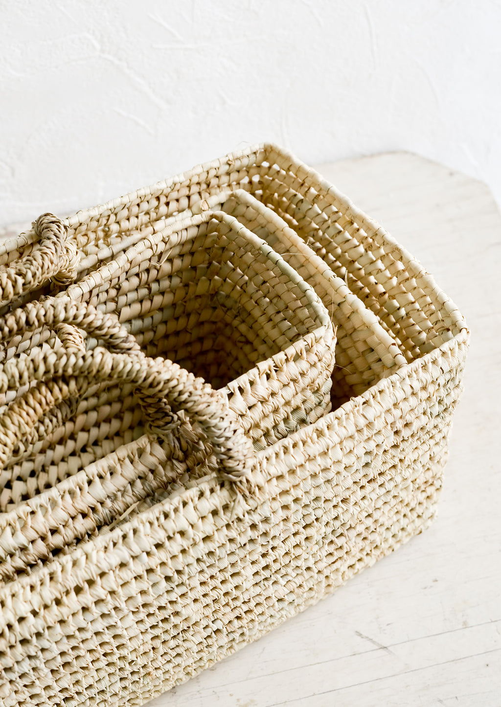 3: Palm leaf baskets in narrow, rectangular shape, nested together.
