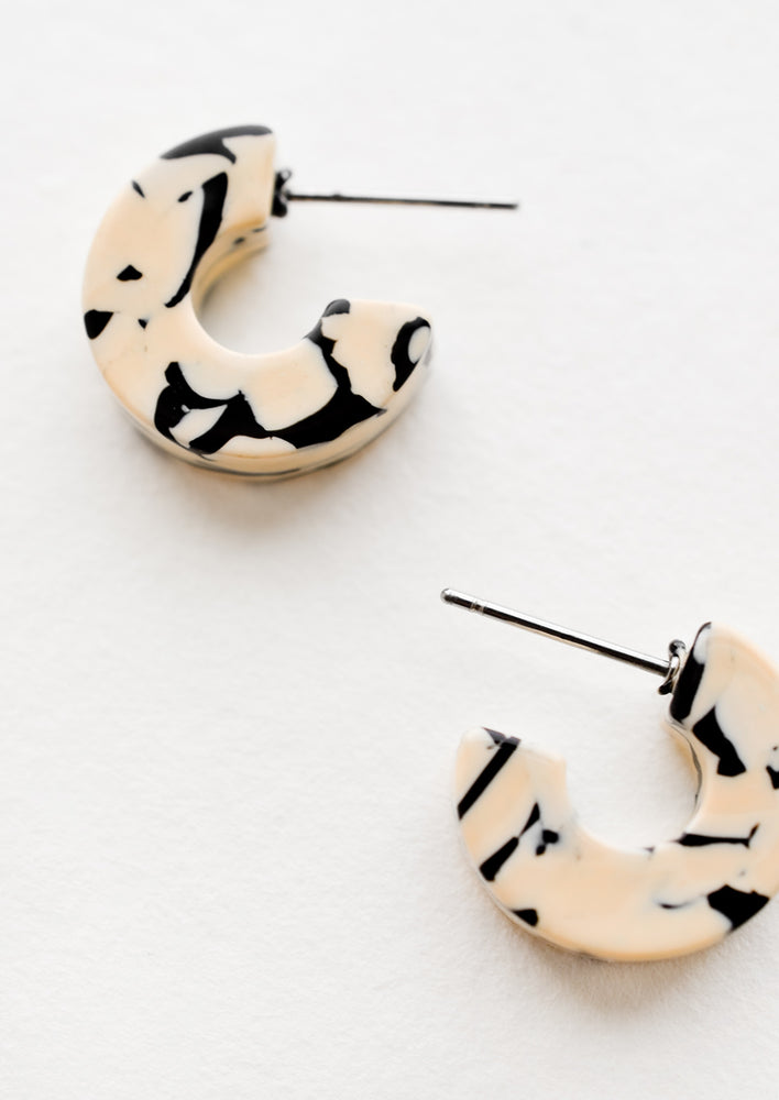 3: A pair of small acetate hoop earrings in tan and black marble.
