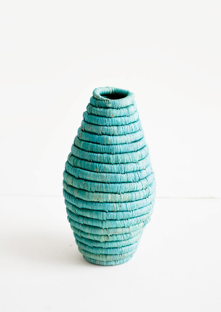 Tall vase made from horizontal coils of woven natural grass in aqua