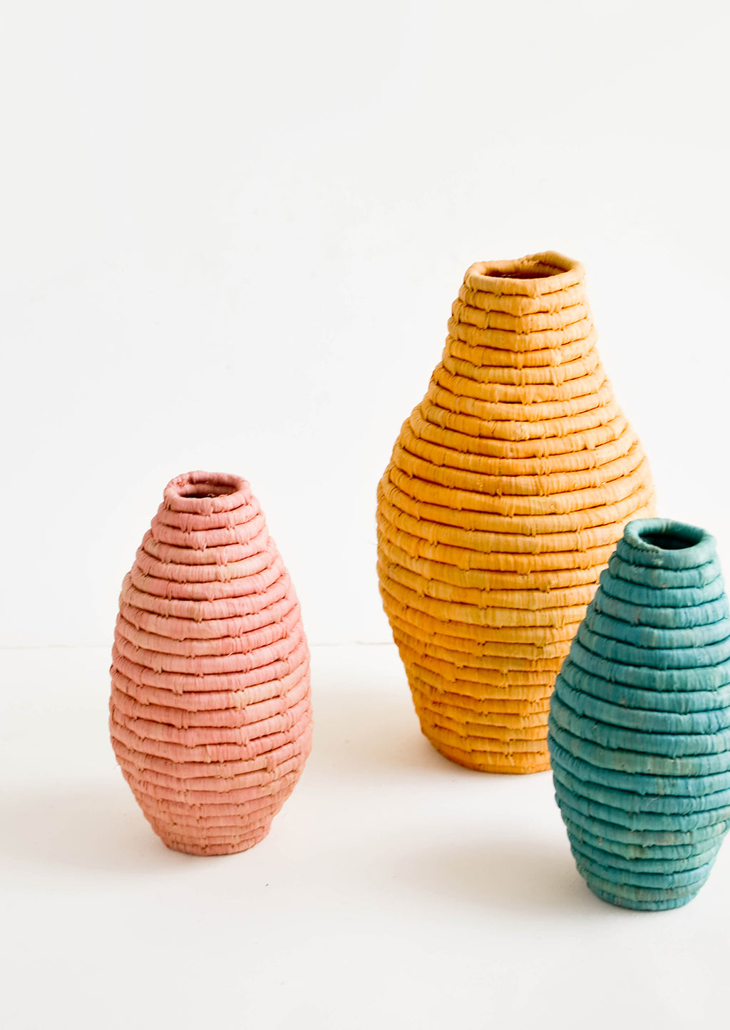 1: Three vases in varying sizes, made from horizontal coils of woven natural grass