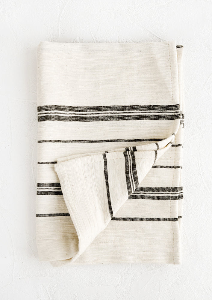 A folded natural cotton hand towel with black stripes.