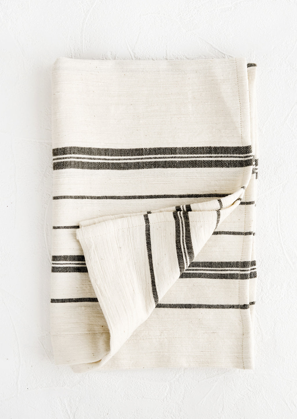 Charcoal: A folded natural cotton hand towel with black stripes.