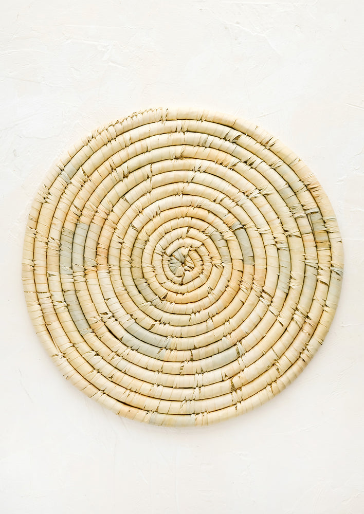 A round placemat made from natural dried straw.