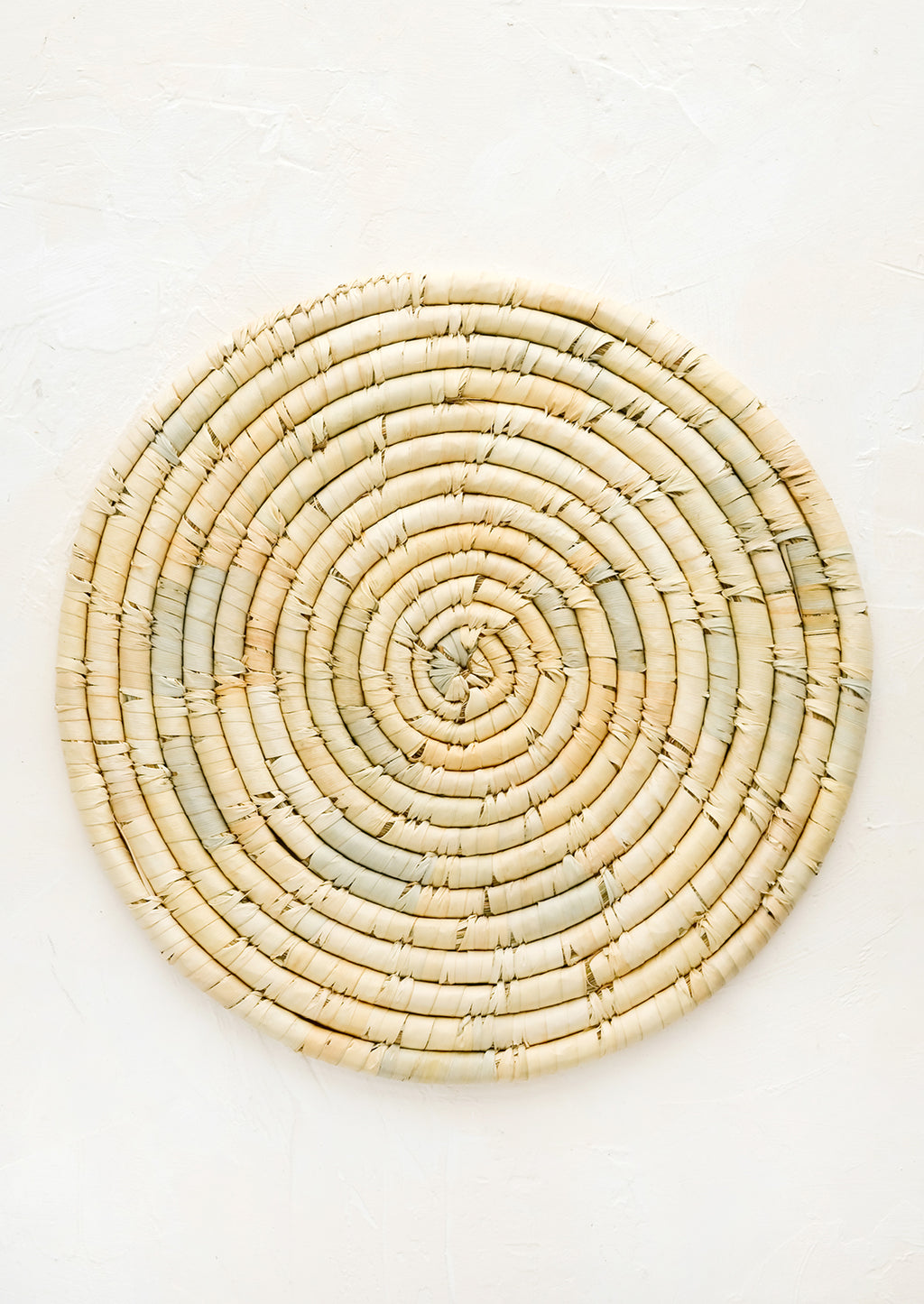1: A round placemat made from natural dried straw.