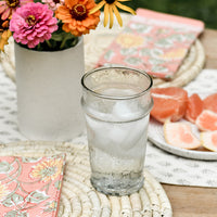 2: A table setting with round straw placemats and water glass.
