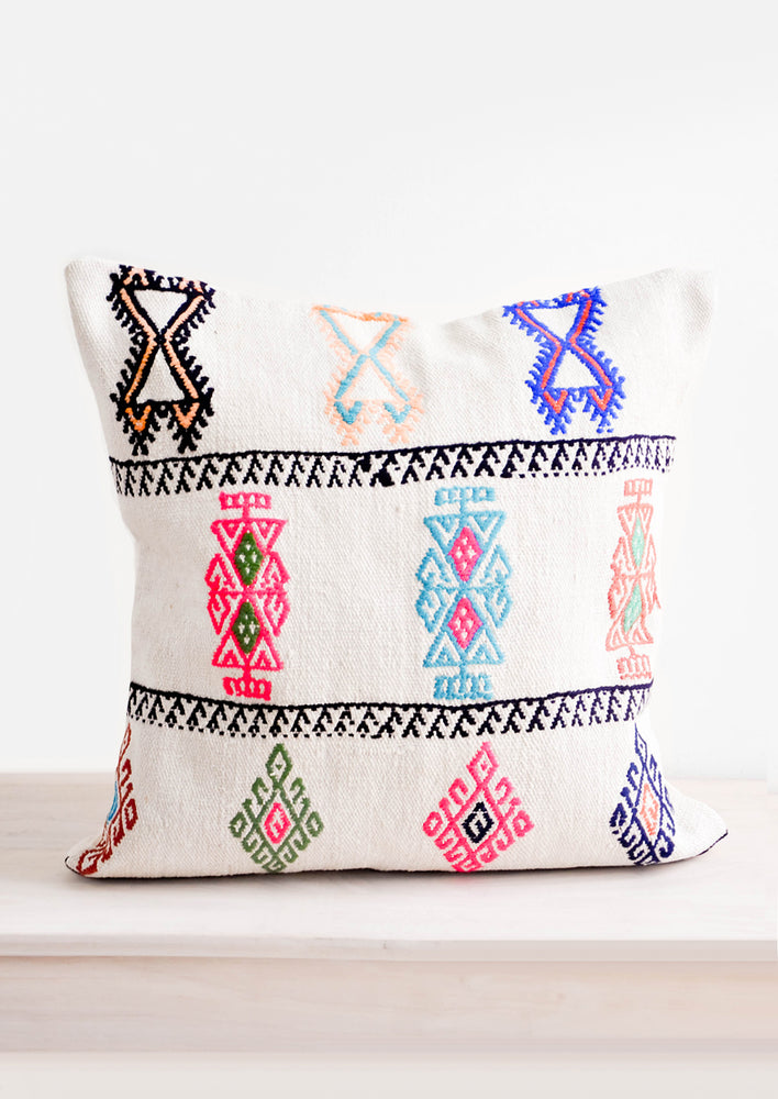 Square throw pillow with neon embroidery on ivory background