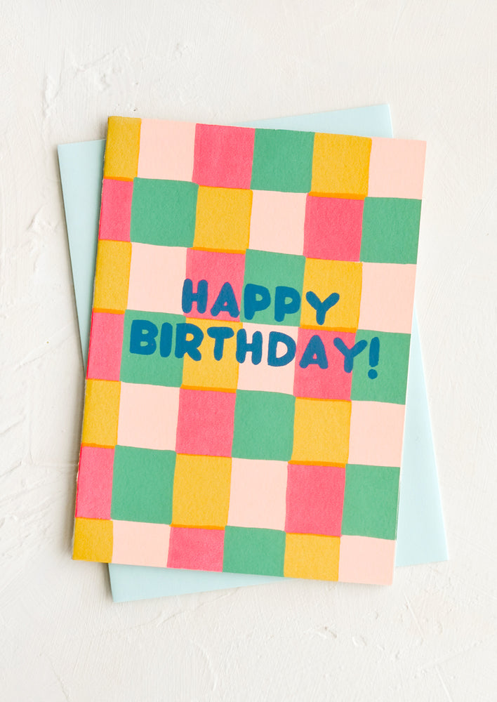 A greeting card with colorful square print background and "HAPPY BIRTHDAY!" text.