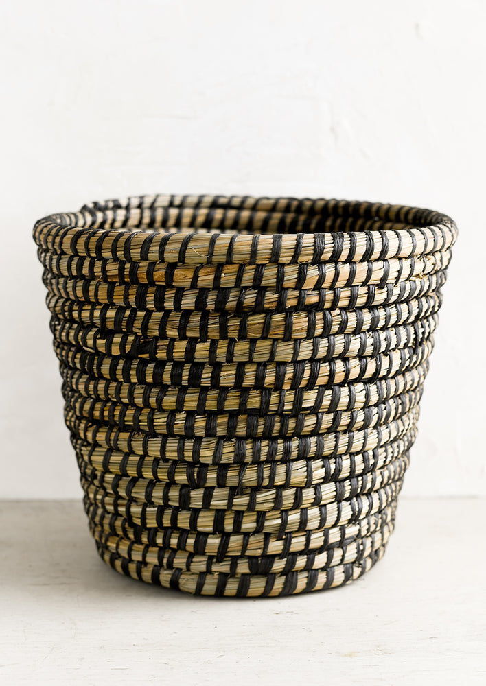 A tapered seagrass basket with woven black detailing.