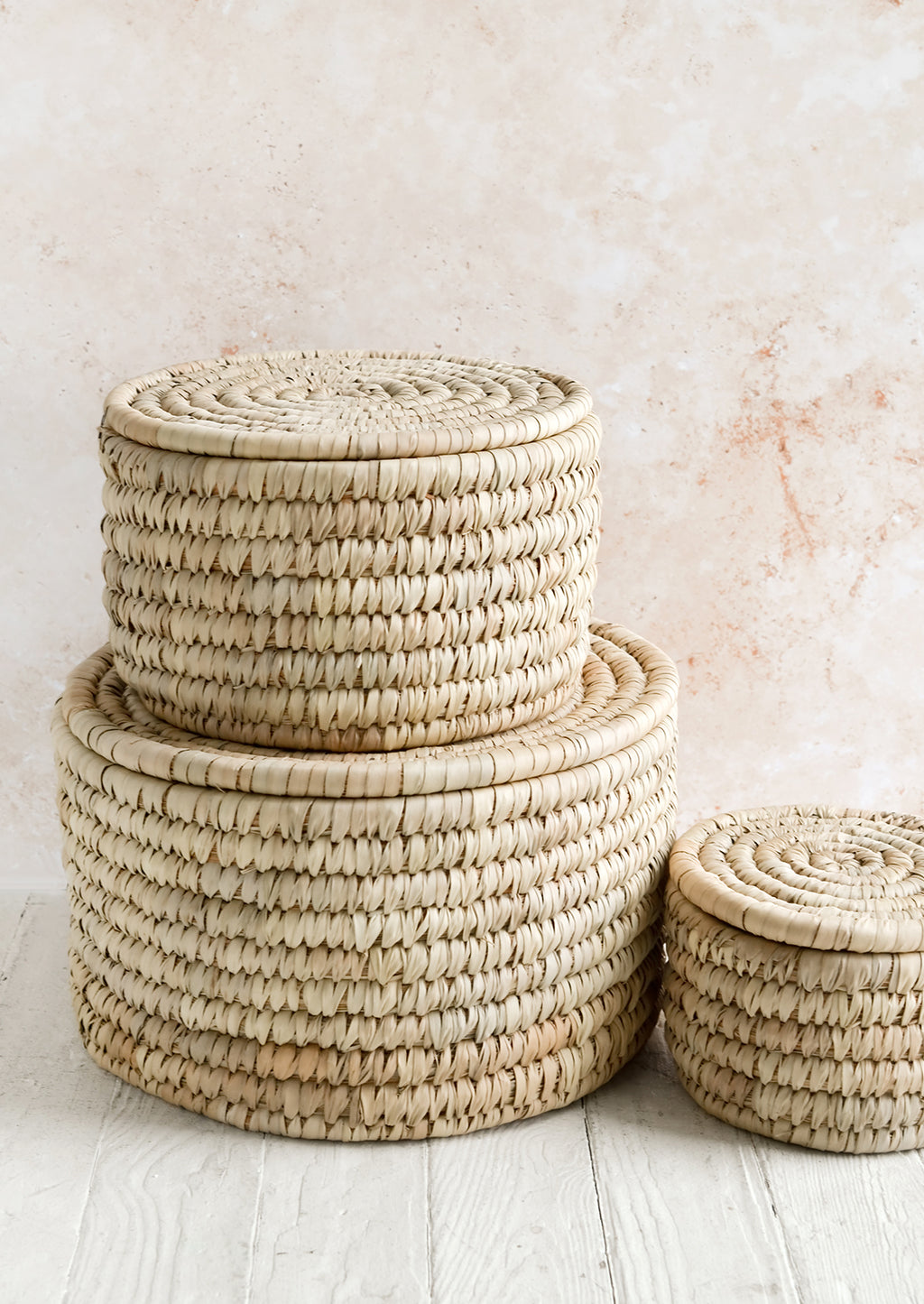 2: Three round, palm leaf storage baskets with lids in incremental sizes.