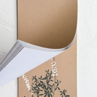 2: A brown plain notebad with floral print at the bottom edge.