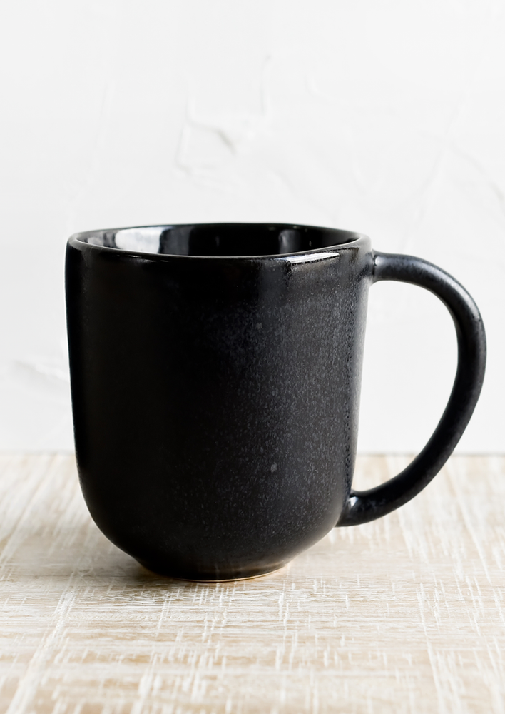 A black ceramic mug in satin glaze with glossy top rim.