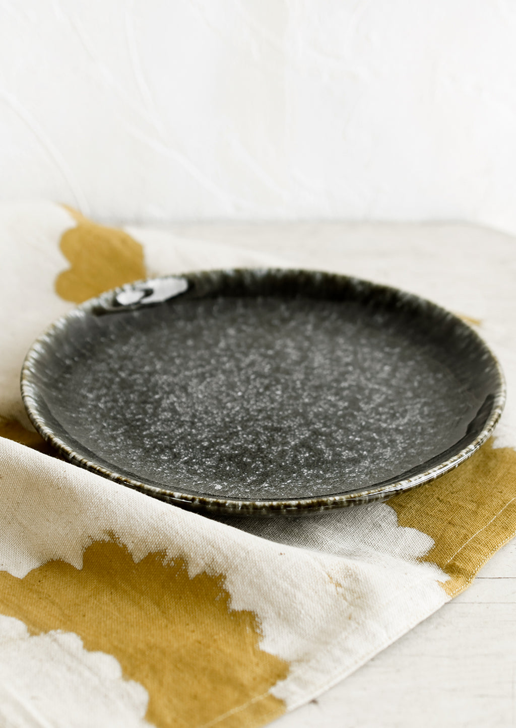 2: A round plate in glossy black speckled glaze.