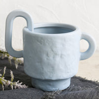 1: A sky blue planter with irregular texture and asymmetric handle detail.
