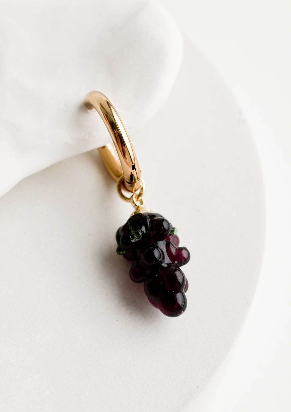 Grape: A single earring with glass grape charm on gold huggie hoop.